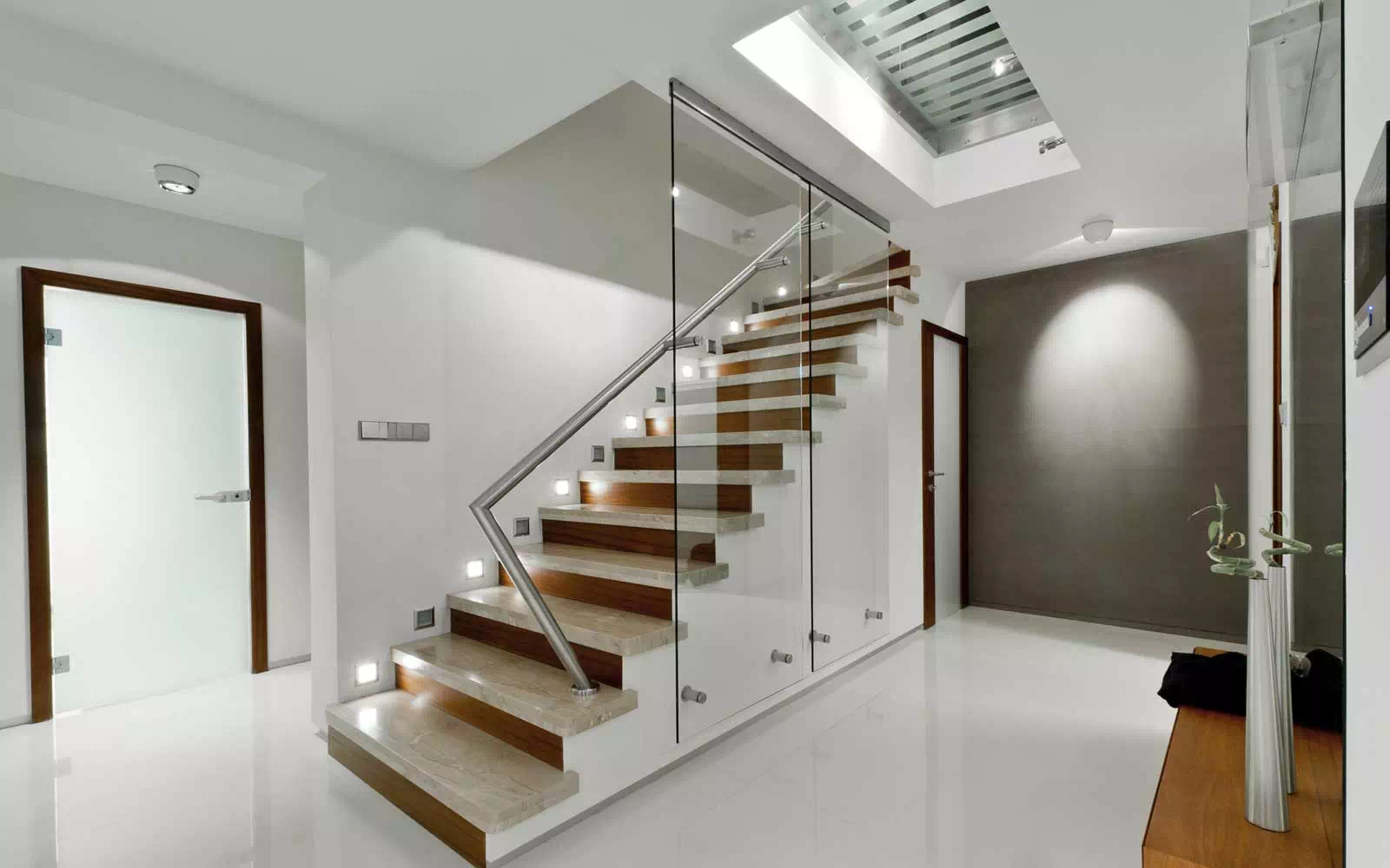 Escalier moderne en bois avec rampe en verre dans un hall lumineux