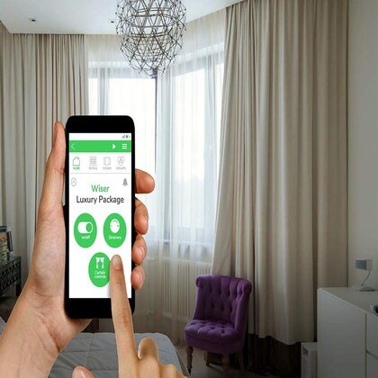 Personne utilisant un smartphone pour contrôler l'éclairage dans un salon avec des rideaux beiges et un fauteuil violet